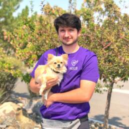 Eddie holding golden pomeranian in his arms.