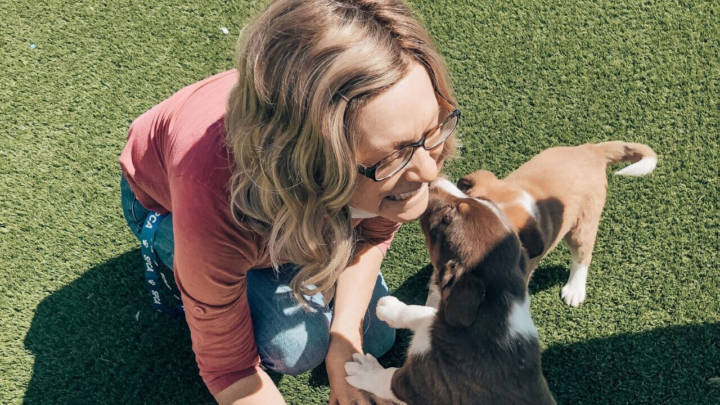 Woman Smiling Kissing Puppies.